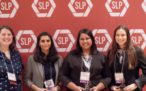 Four women smiling holding awards in front of a red backdrop.